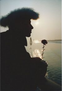 Woman standing by sea against sky