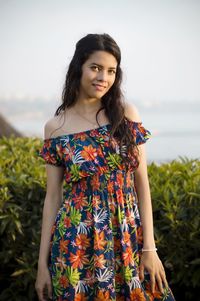 Young woman standing against plants