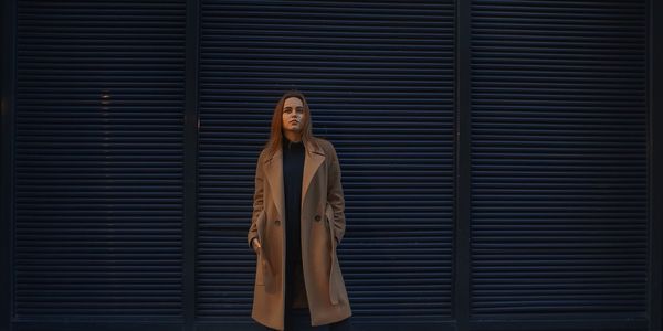 Portrait of a young woman standing against brick wall