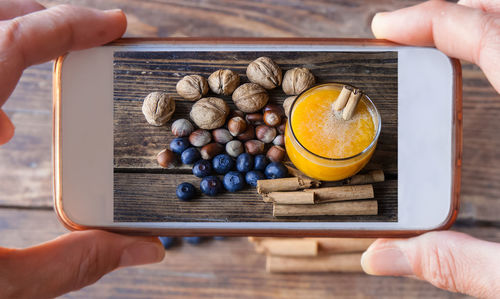 Cropped hands photographing food and drink with smart phone on table