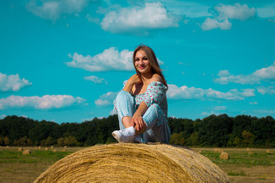 A young girl sits on a hay bale and smiles