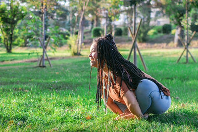 Young woman is sitting on a grass and doing yoga exercise. healthy lifestyle outdoors.
