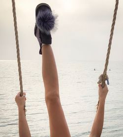 Woman holding umbrella at beach against sky