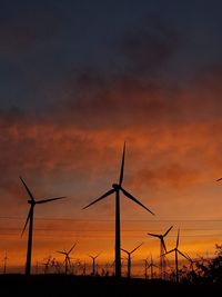 Low angle view of electricity pylon against sky during sunset