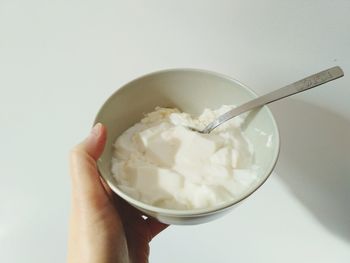 Close-up of hand holding ice cream against white background