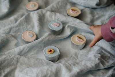 Cropped hand reaching cupcake on fabric