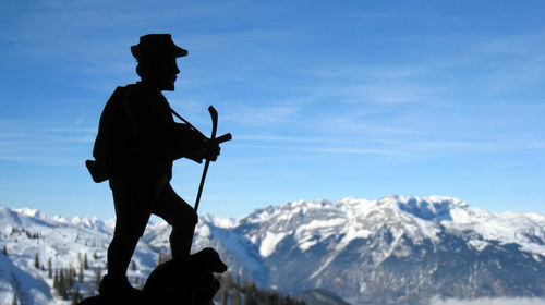 Silhouette figurine by snow covered mountains against sky