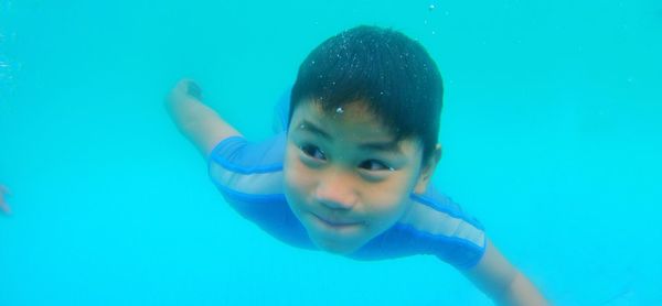 Close-up portrait of smiling boy swimming underwater