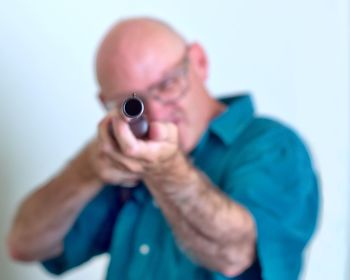 Close-up of man shooting with rifle against white background