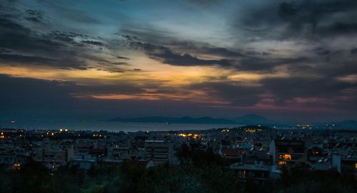 Illuminated cityscape against sky at sunset