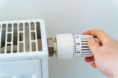 Hand turns regulator on heating radiator. saving resources and heat energy because of energy crisis