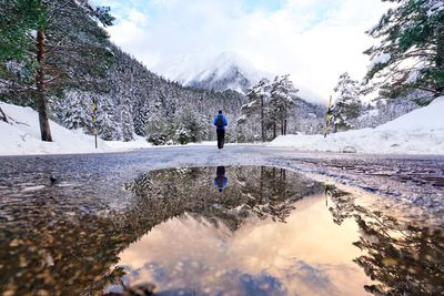 Rear view of man standing on snow covered mountain against sky