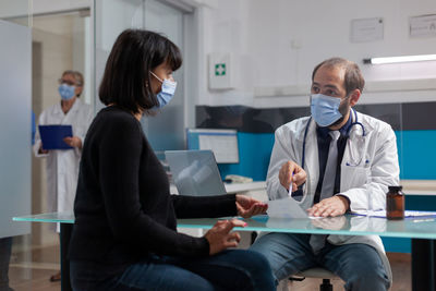 Doctor wearing mask examining patent in clinic