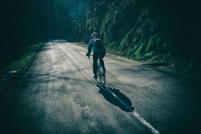 Rear view of man riding bicycle on road