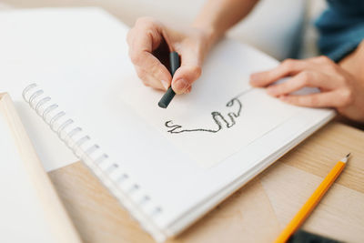 Midsection of woman writing in book