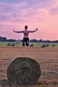 Full length of man with arms raised on field against sky