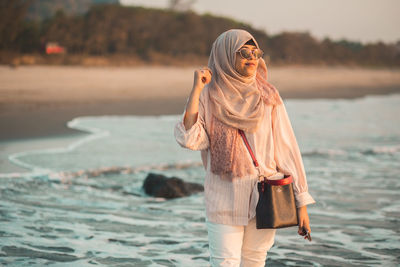 Portrait of young woman standing at beach