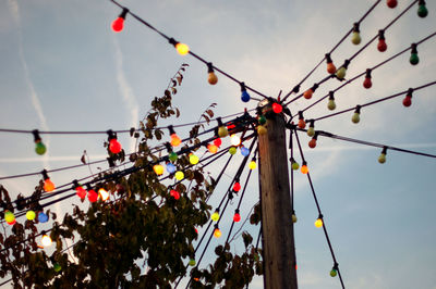 Low angle view of hanging lights against sky