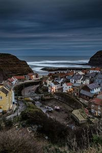 High angle view of town by sea against cloudy sky at dusk