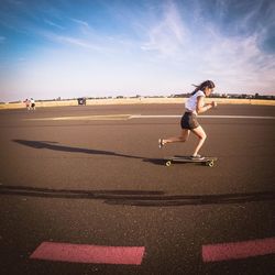 Woman skateboarding on road in city