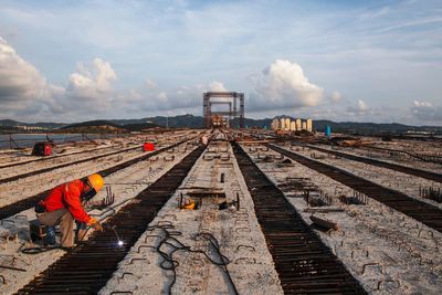 Railroad tracks at construction site against sky