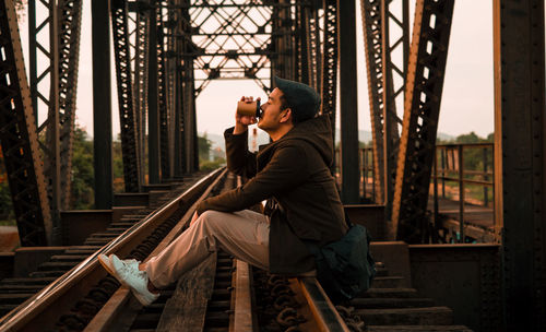 Man photographing with mobile phone sitting outdoors