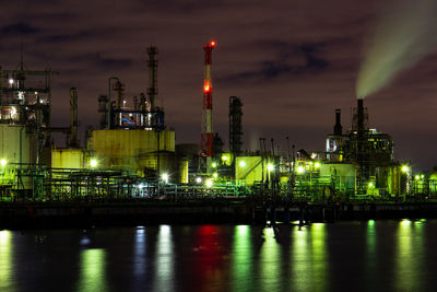 Illuminated factory against sky at night