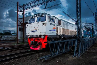 Train on railroad tracks against cloudy sky