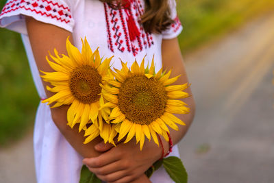 Midsection of woman holding sunflower