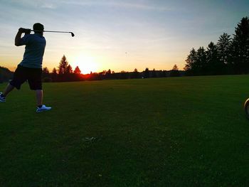 People on grassy field during sunset