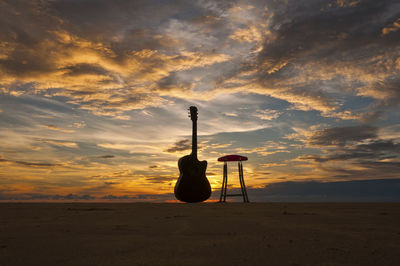 Silhouette lifeguard hut on beach against sky during sunset