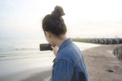 Side view of man standing at beach against sky