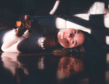 Portrait of young woman holding violin while lying down at home