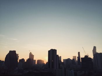 Silhouette buildings against clear sky during sunset