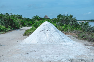 Heap sand on roadside against sky