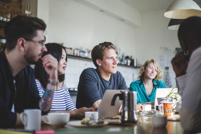 Young it experts looking away at creative workplace