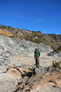 Rear view of man on standing on field against rock mountains