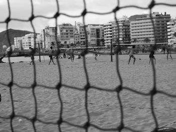 Buildings in city seen through chainlink fence