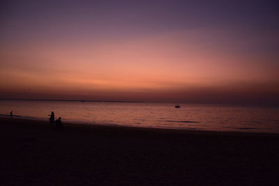 Silhouette people on beach against sky during sunset