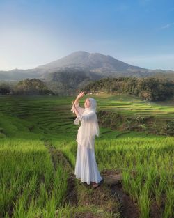 Woman with umbrella standing on field