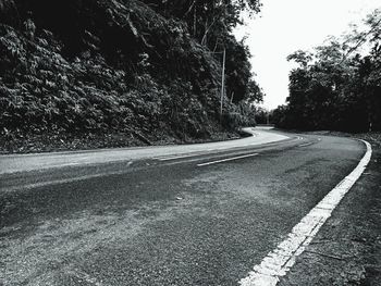 Road by trees against sky