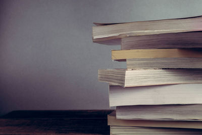 Close-up of books stacked on table against wall