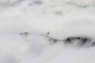 Scenic view of mountains against cloudy sky during foggy weather