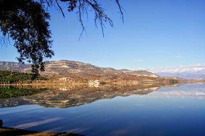 Scenic view of lake and mountains against blue sky