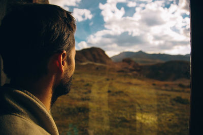 Portrait of young man looking away against sky