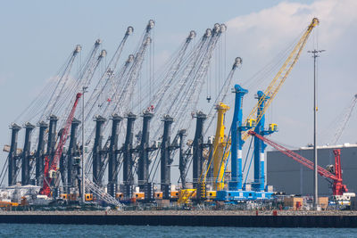 Cranes at commercial dock against sky