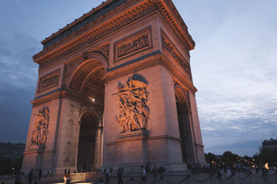 Low angle view of arc de triomphe against sky in city at dusk