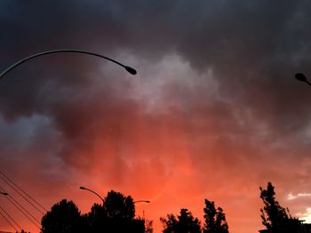 Low angle view of silhouette trees against dramatic sky