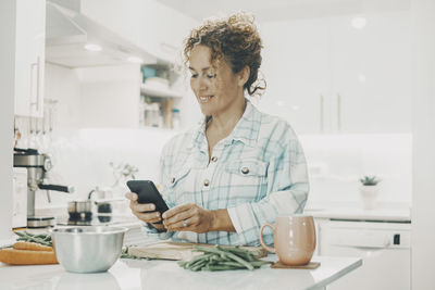 Young woman using mobile phone while sitting at home