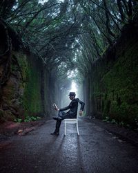 Man sitting on road amidst trees